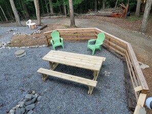 Una terraza de madera con una mesa y dos sillas Adirondack.