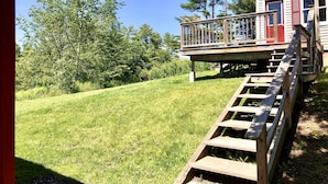 A wooden deck with a staircase leading to a house with a red door. - Quaint & Cozy 1830s Cape- Central Location! (Wiscasset)