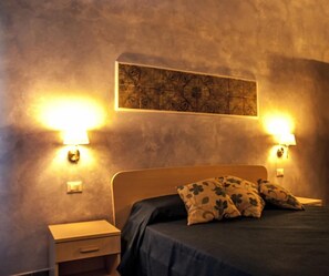 A bedroom with a bed, two bedside lamps, and a wall-mounted artwork. - Blu Tropea Maison (Tropea)