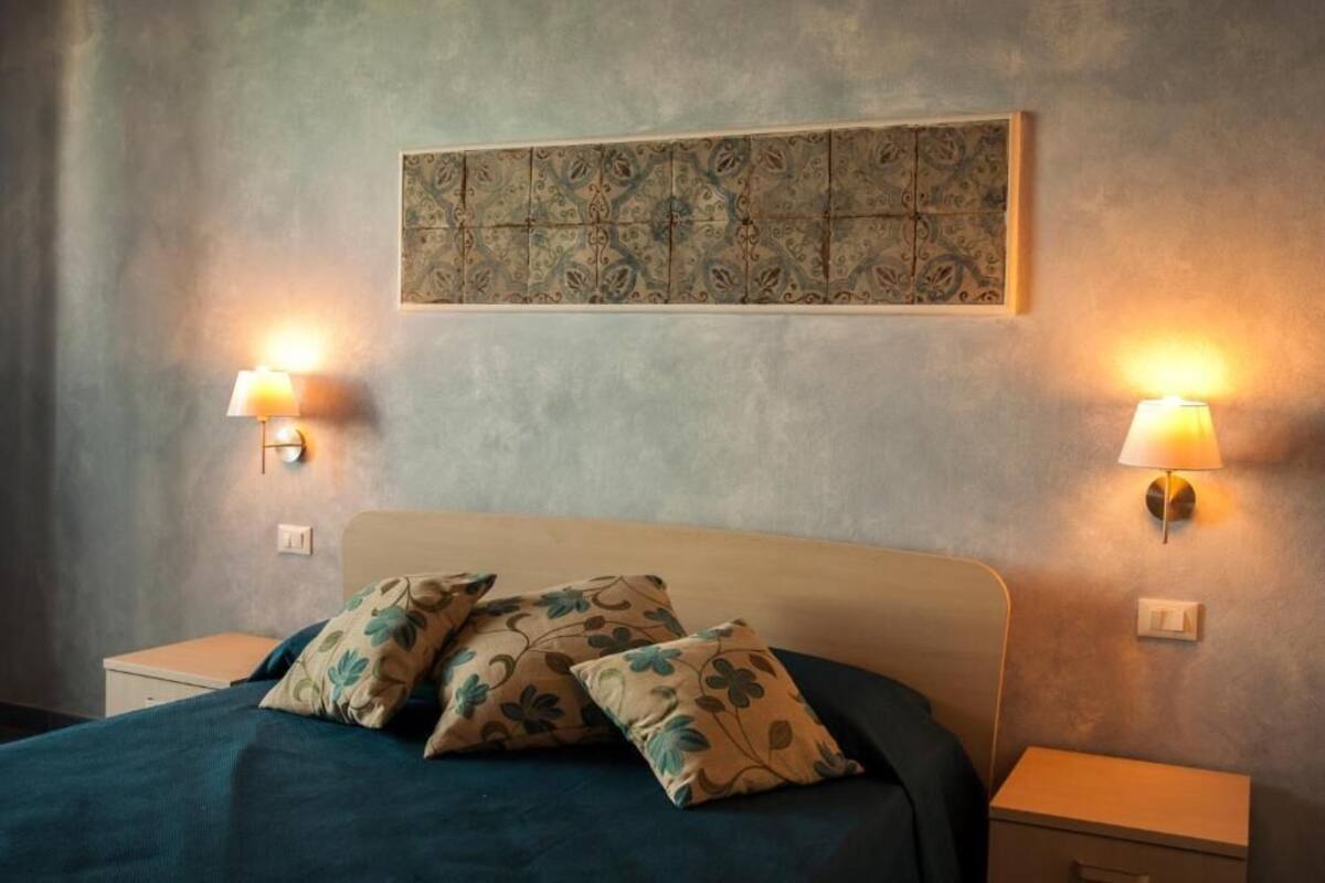 A bedroom with a bed, two nightstands, and wall-mounted lamps.