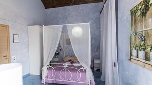 Quarto com uma cama de dossel, um toldo branco, uma porta de madeira, um guarda-roupa branco e uma janela com uma planta.