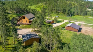 Een lodge met een groot terras, omringd door dicht bos en een berg op de achtergrond.