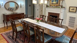A dining room with a wooden table, chairs, a chandelier, a fireplace, and a mirror. - Spacious restored 1914 historic home steps from the beach. (Cape Charles)