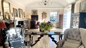 Um quarto amplo com duas poltronas elaboradas, uma mesa de madeira e um candelabro.