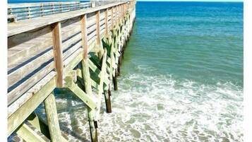Un muelle de madera que se adentra en aguas tranquilas bajo cielos despejados.