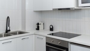 Una cocina moderna con armarios blancos, electrodomésticos de acero inoxidable, microondas y horno empotrado.