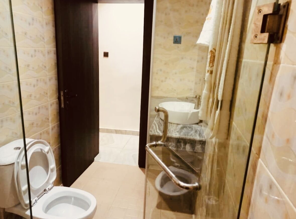 A bathroom with a toilet, a sink, and a glass shower enclosure.