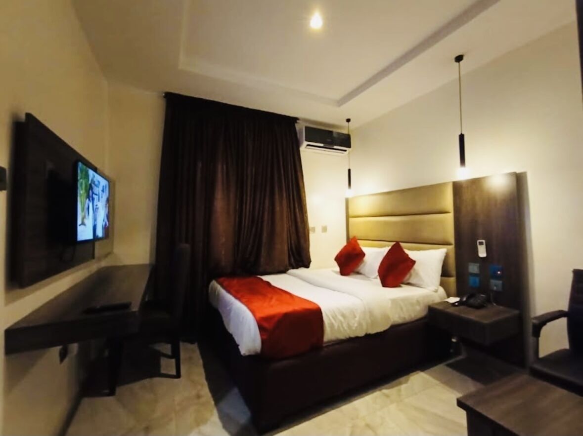 Una habitación de hotel con una cama grande, un escritorio, un televisor y un armario.