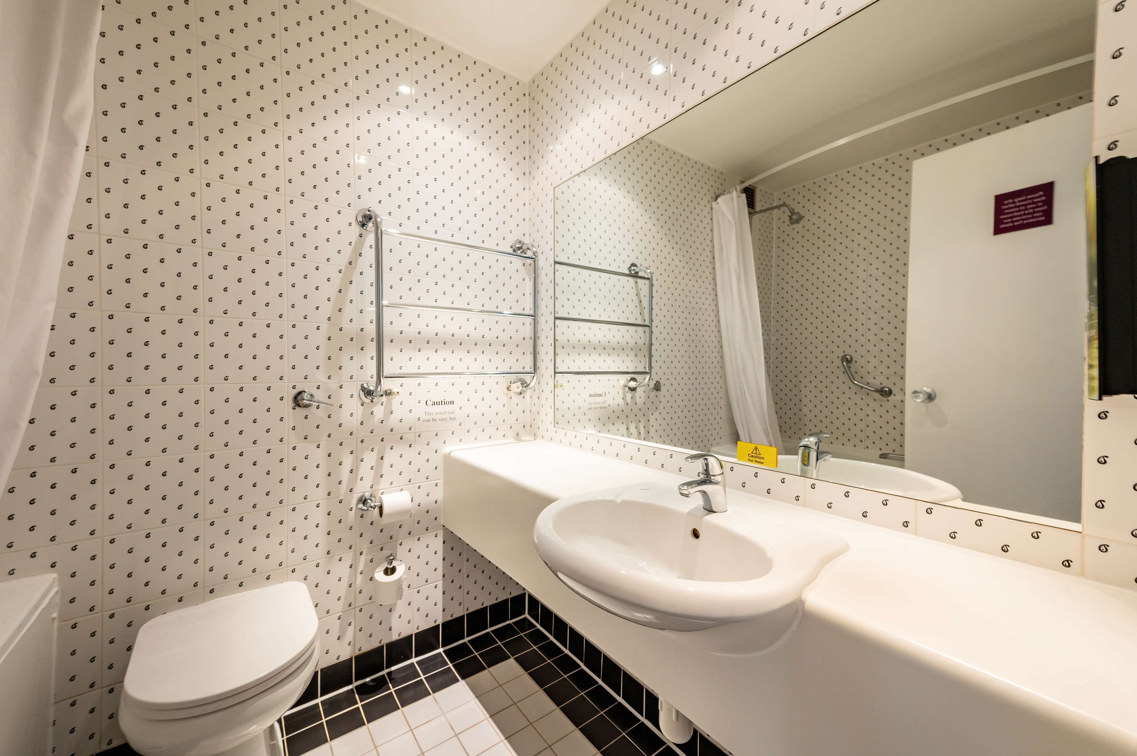 A bathroom with a white toilet, a sink with a mirror, and a shower area.