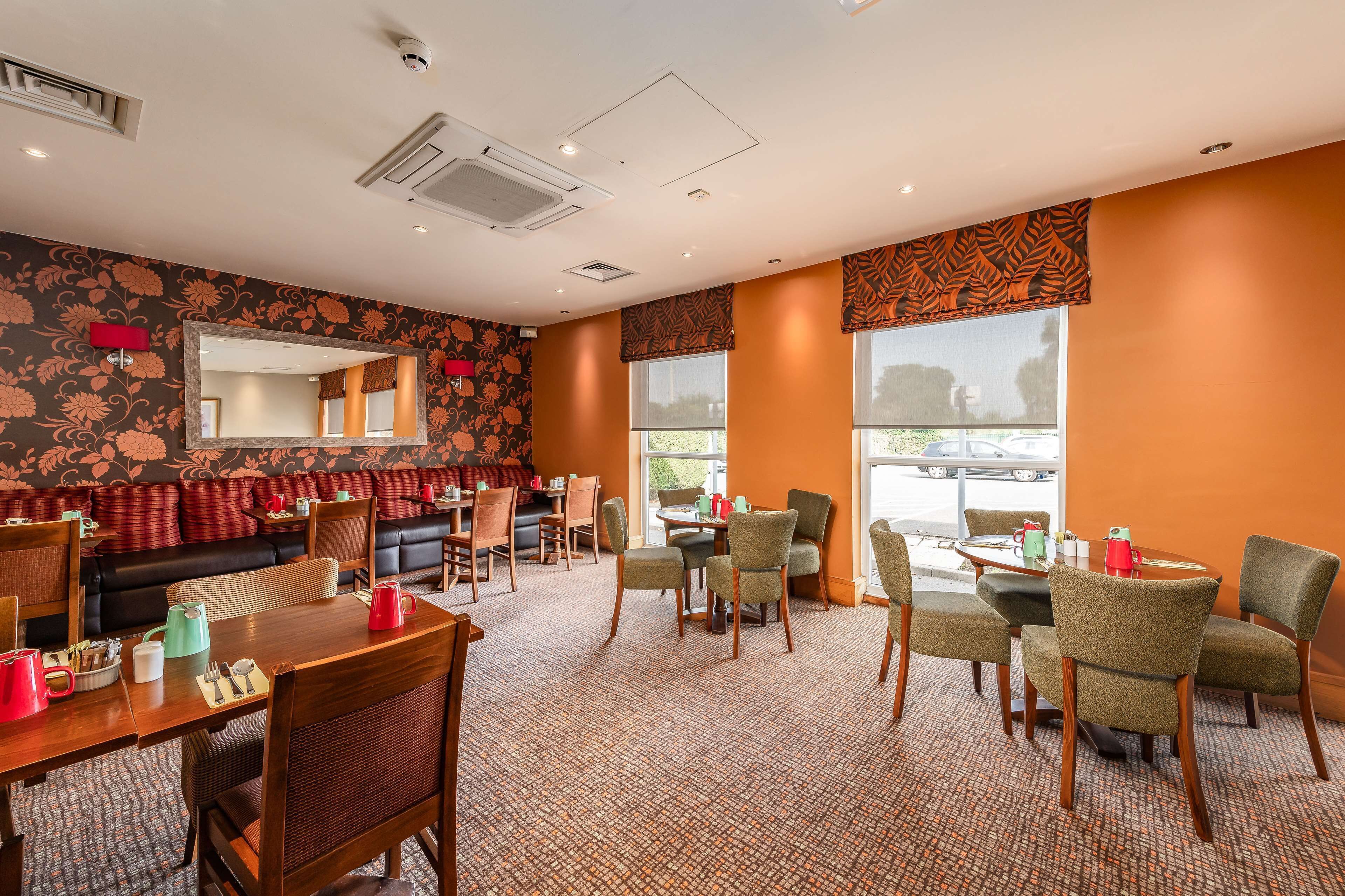 A hotel room with a sofa, dining table, chairs, and a large window.