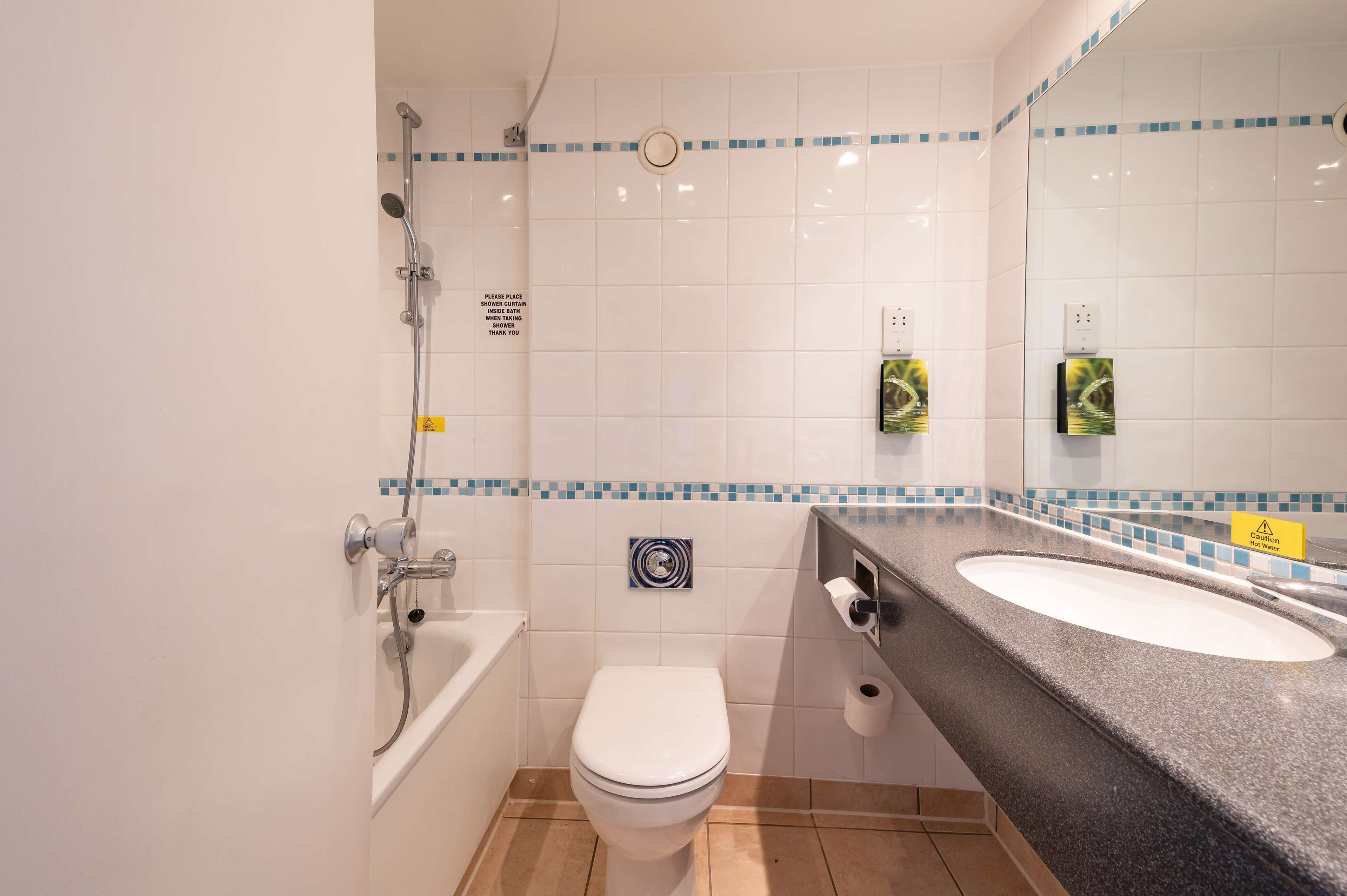 Une salle de bain avec une baignoire, des toilettes et deux lavabos.