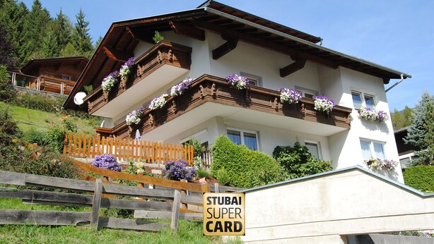 A two-story chalet with wooden balconies, flower boxes, and a wooden fence. - holiday apartment Elferblick (Fulpmes)