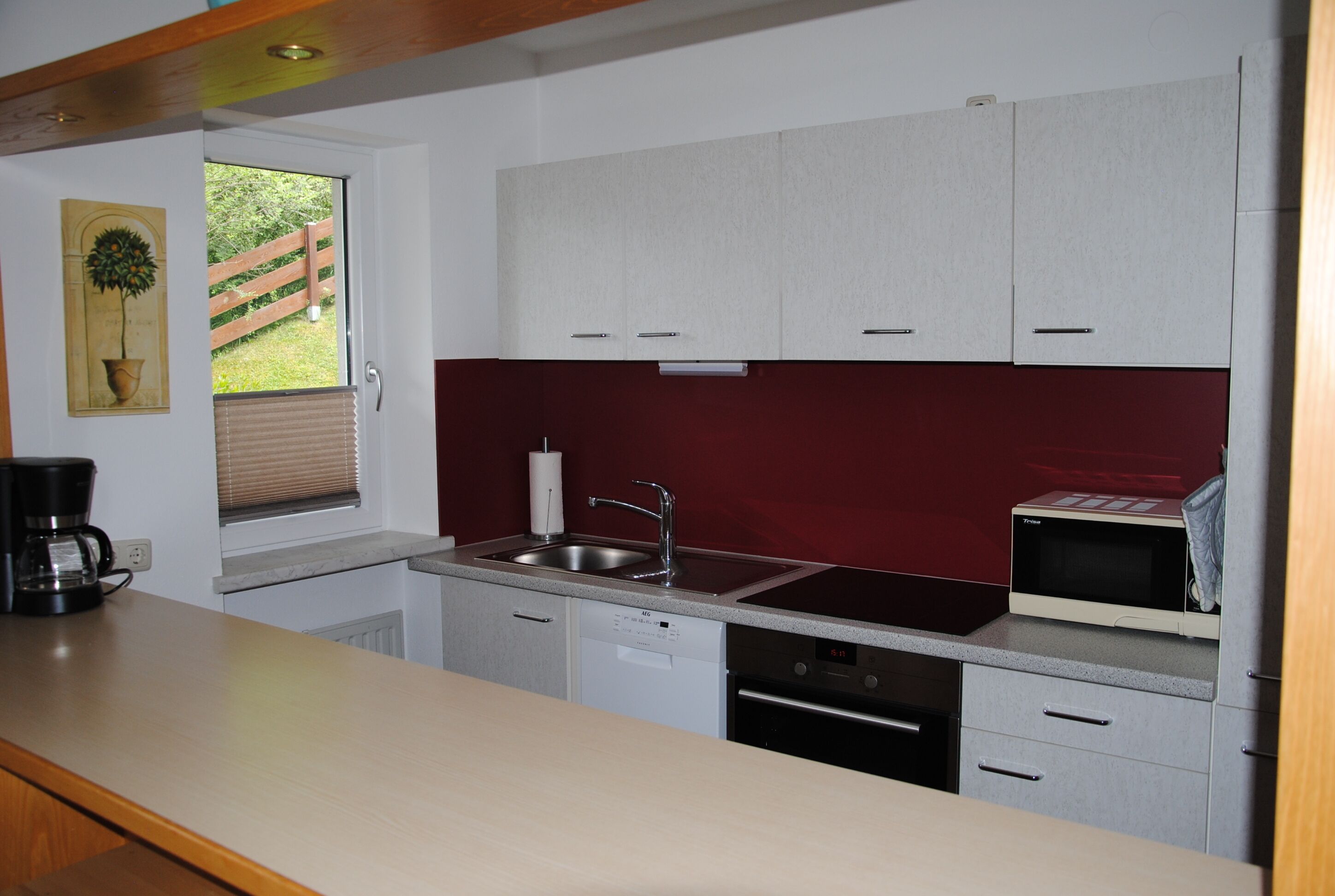 A compact kitchen with white cabinets, a stainless steel sink, a microwave, and a dishwasher.