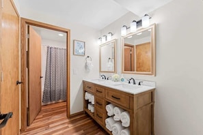 Een moderne badkamer met een houten wastafelmeubel, twee wastafels en een grote spiegel.