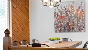 Uma sala de jantar com uma mesa de madeira, cadeiras e um lustre.