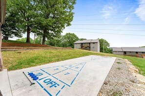 A shuffleboard court with a 'OFF' sign, trees, and buildings in the background.