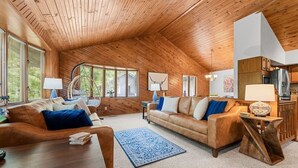 Uma sala de estar aconchegante com tetto de madeira, um sofá, uma mesa de centro e um tapete.