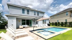 A modern two-story house with a swimming pool, outdoor seating, and a covered patio area.