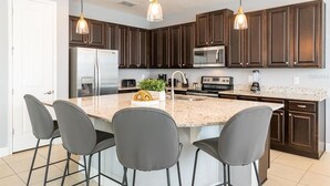 A modern kitchen with dark wood cabinets, a granite countertop, and a central island with bar stools.