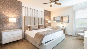 A modern bedroom with a large bed, a ceiling fan, and a stone-patterned wall.