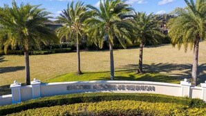 A sign for Encore Resort & Residences with a well-manicured lawn and palm trees.