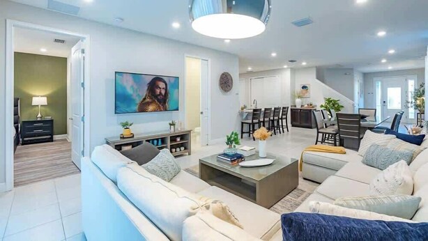 Ein modernes Wohnzimmer mit einer Couch, einem Couchtisch und einem an der Wand befestigten Fernseher.
