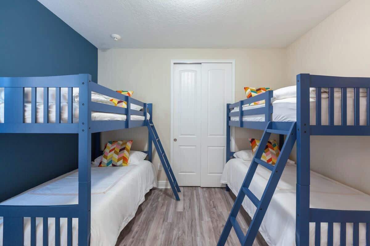 Een kamer met stapelbedden, een witte deur en een houten vloer.