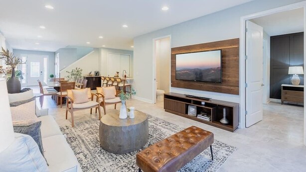 A modern living room with a flat-screen TV, comfortable seating, and a staircase leading to another level. - Magical 6BR PetFriendly @Encore Near Disney 7722 (Kissimmee)