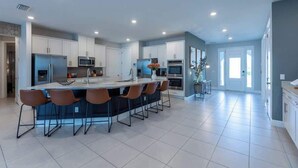 Una cocina moderna con una isla central, armarios blancos y electrodomésticos de acero inoxidable.