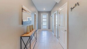 A hallway with a wooden console table, a framed picture, and a 'Family' sign on the wall.