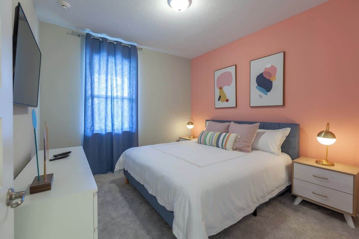 Une chambre à coucher avec un lit, des tables de chevet, un téléviseur et des œuvres d’art accrochées au mur.