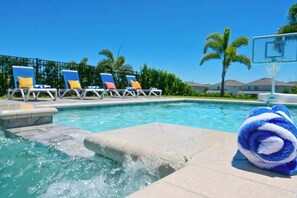 Una piscina con sillas de descanso y un aro de baloncesto.