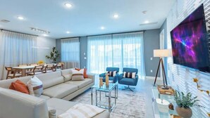 Ein modernes Wohnzimmer mit einer Couch, Sesseln, einem Couchtisch und einem Fernseher.