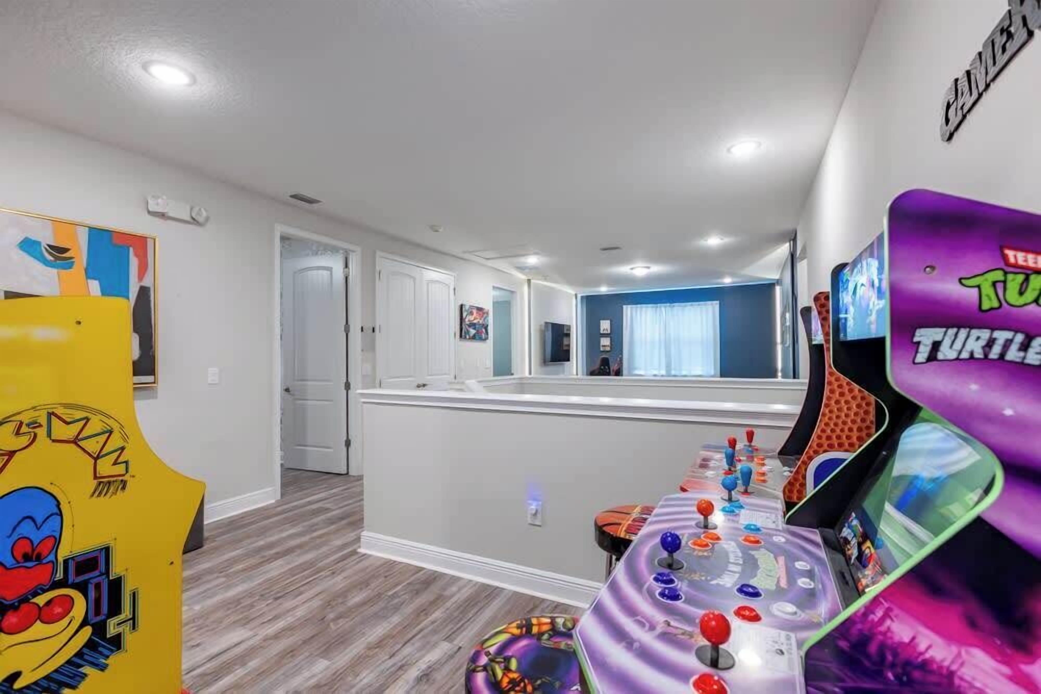 A room with a gaming console, a colorful abstract painting, and a Turtles-themed wall decoration.