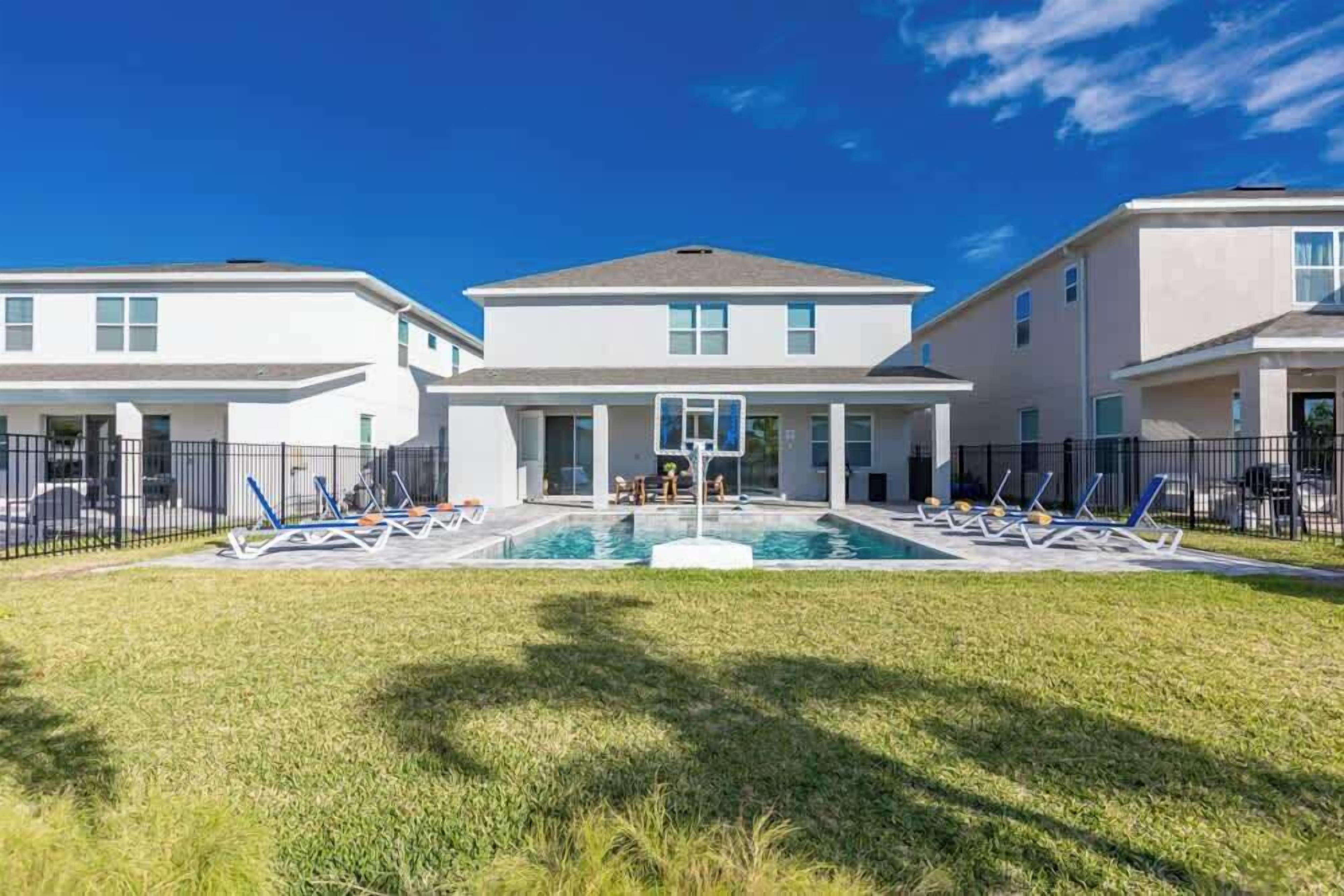 A modern residential building with a swimming pool and lounge chairs.