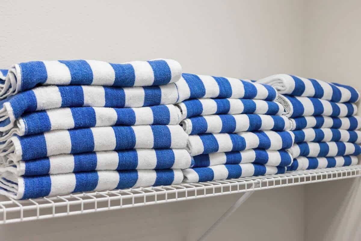 A stack of blue and white striped towels on a white metal shelf.