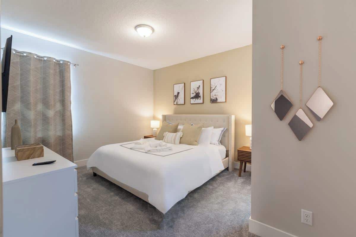 Ein Schlafzimmer mit einem Bett, Nachttischen, einem Fernseher und Kunstwerken an der Wand.