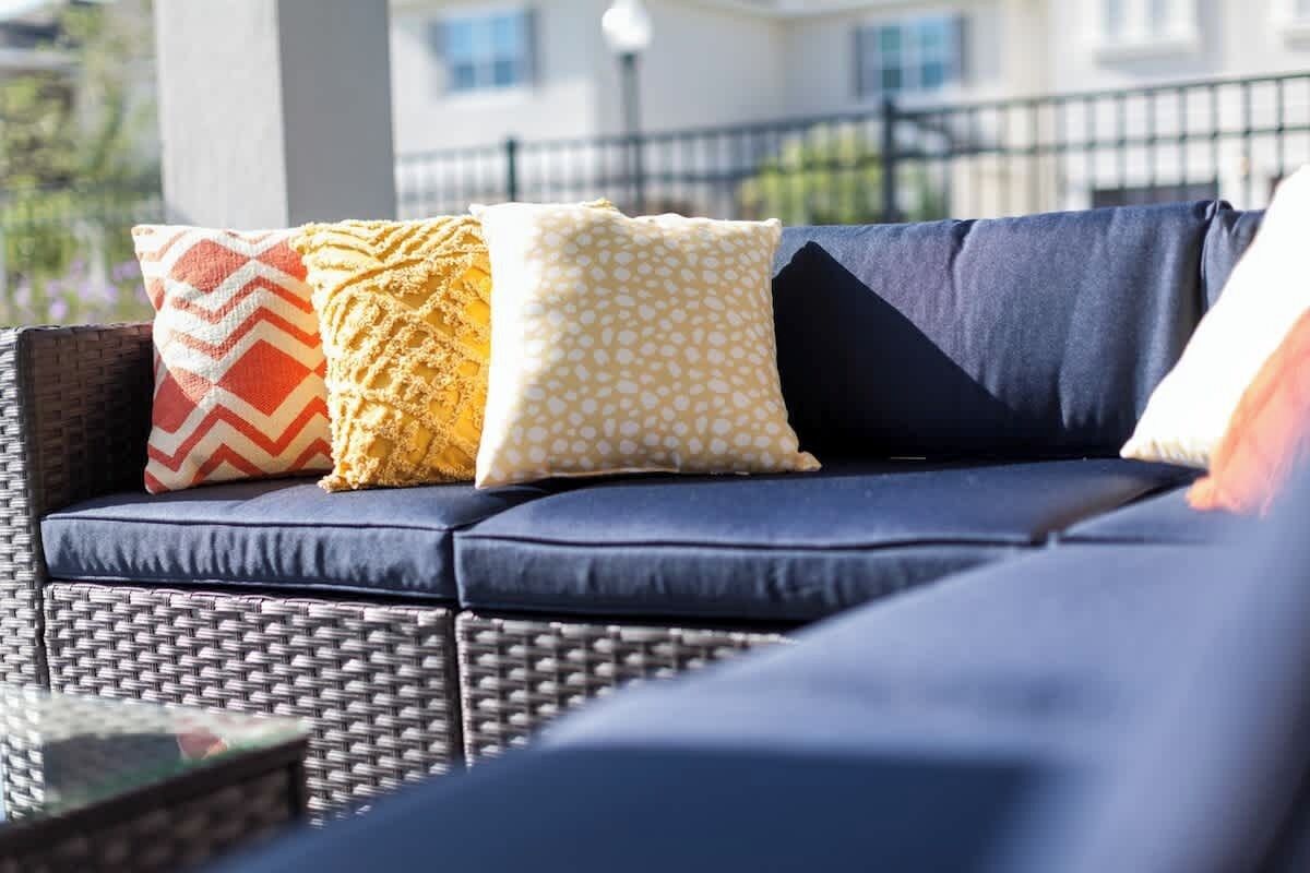 Ein dunkelblaues Outdoor-Sofa mit gemusterten Kissen.