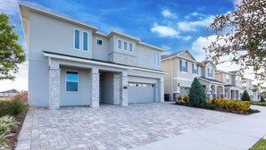 Ein modernes, zweistöckiges Haus mit Garage, Steinaußenwand und befestigter Auffahrt.