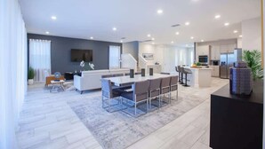 Un salon moderne comprenant un coin repas, une cuisine et un escalier menant à l’étage supérieur.