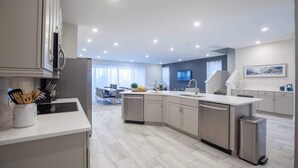 Une cuisine moderne dotée d’un îlot central, d’appareils électroménagers intégrés et d’un coin repas à l’arrière-plan.