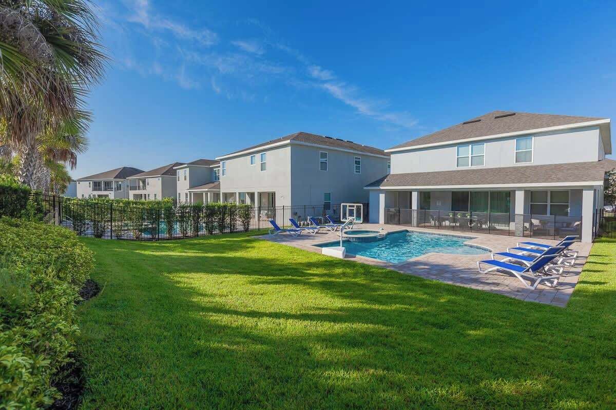 A residential area with a swimming pool, multiple houses, and a well-maintained lawn.