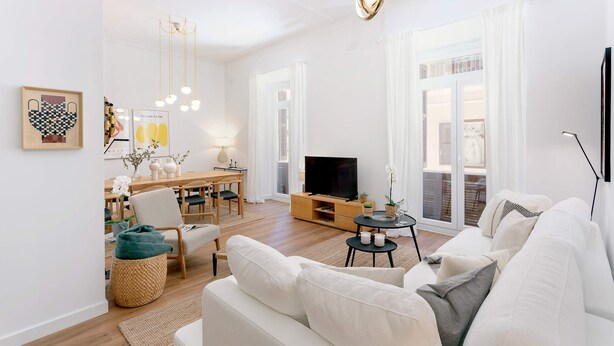 Una sala de estar moderna con sofá, televisor y zona de comedor.
