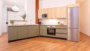 Una cocina moderna con horno empotrado, microondas y refrigerador de acero inoxidable.