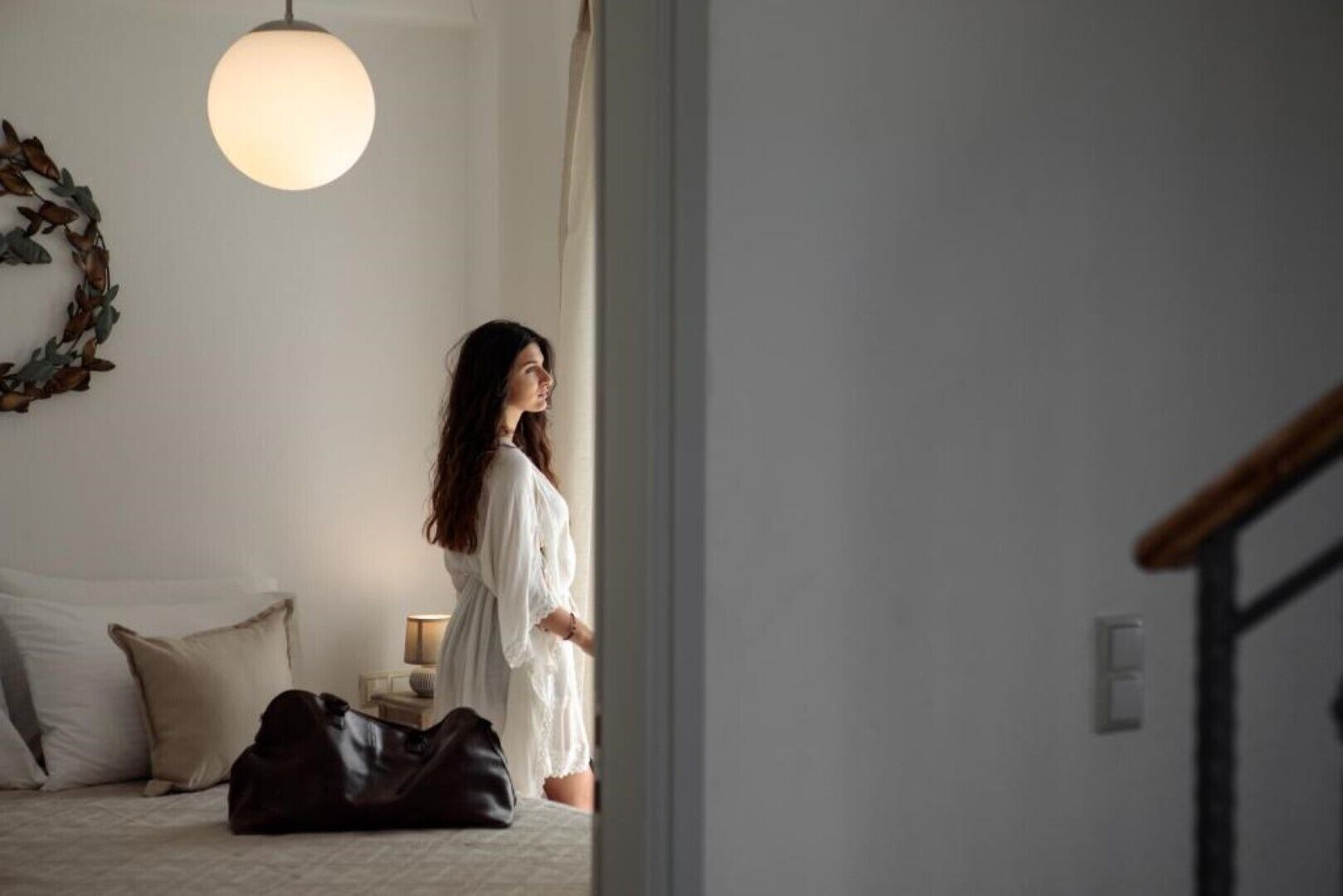 A room with a bed, a lamp, and a large circular light fixture.