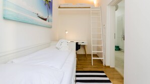 A bedroom with a bunk bed, a painting of a beach scene, a white desk with a lamp, and a ladder. - Vienna Residence, Adamberg - Leopoldstadt #6310 (Vienna)