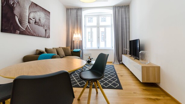 A modern living room with a dining area, a large painting, a television, and a window with curtains. - Vienna Residence, Adamberg - Leopoldstadt #6310 (Vienna)
