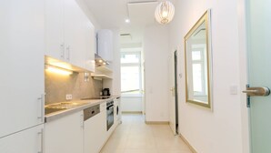 A modern kitchen with white cabinets, a built-in oven, and a stainless steel range hood. - Vienna Residence, Adamberg - Leopoldstadt #6310 (Vienna)