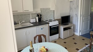 Eine kleine Küche mit weißen Schränken, einem Gasherd, einem Toaster und einem Fernseher.