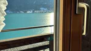 Una terraza de madera con baranda de metal que da vista a un cuerpo de agua y montañas.